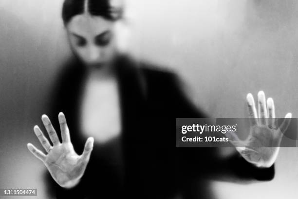 female gesturing fear behind frosted glass - victim silhouette stock pictures, royalty-free photos & images