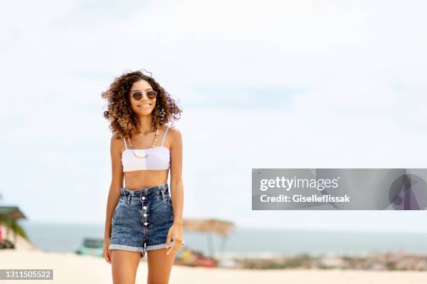 adolescente sorridente caminhando ao longo de uma praia no verão - calção - fotografias e filmes do acervo
