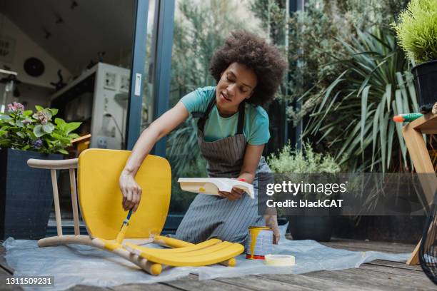 de vrouw schildert een oude stoel in de achtertuin - garden furniture stockfoto's en -beelden