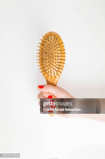 front view of a caucasian woman's hand with red painted nails holding a wooden hair brush on a white background. - hairbrush 個照片及圖片檔