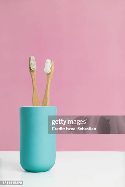 front view of two bamboo toothbrushes placed in a blue ceramic cup. the brushes symbolize life as a couple. - toothbrush imagens e fotografias de stock