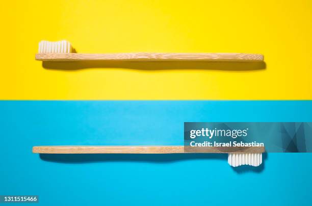 top view of two bamboo toothbrushes on a yellow and blue background. - escova de dentes imagens e fotografias de stock