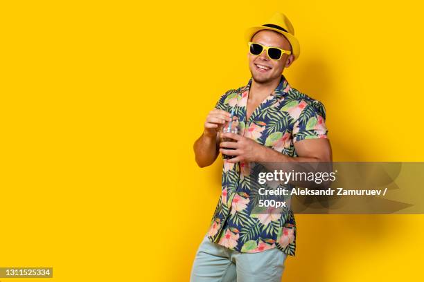 portrait of smiling man wearing sunglasses while standing against yellow background - straw hat stock pictures, royalty-free photos & images