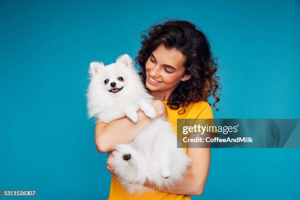 verticale de studio de jeune femme de sourire retenant le petit crabot - chien et maitre photos et images de collection