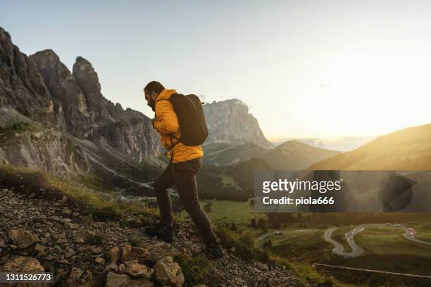 man mountain hiking at sunset on the dolomites: outdoor adventure - hiking stock pictures, royalty-free photos & images