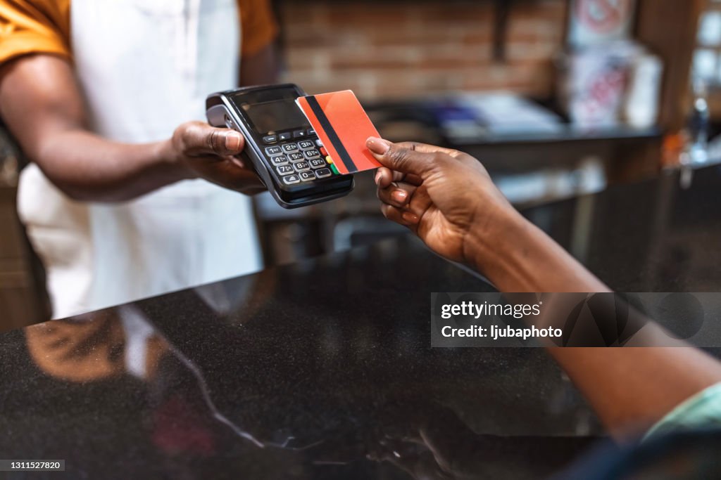 Abgeschnittene Aufnahme einer nicht wiederzuerkennenden Frau, die für ihren Kauf per Karte bezahlt