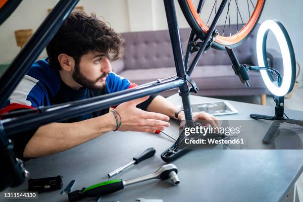 male vlogger filming bicycle tutorial through smart phone at home - home hobbies stock pictures, royalty-free photos & images