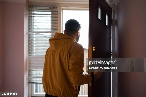 man in yellow jacket opening door - leaving imagens e fotografias de stock