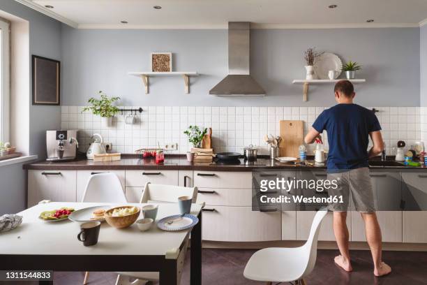 mature man preparing food in kitchen at home - man cooking photos et images de collection