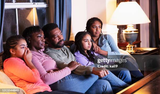テレビを見ている3人の娘を持つアフリカ系アメリカ人の家族 - horror movie ストックフォトと画像
