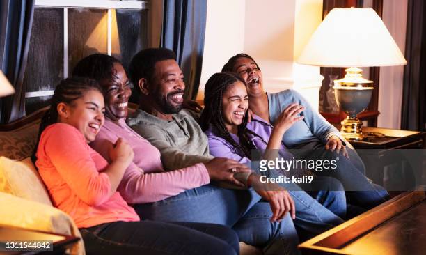 familia afroamericana con tres hijas viendo la televisión - familia viendo television fotografías e imágenes de stock