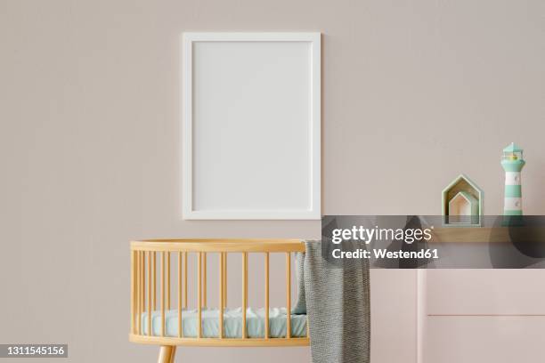 three dimensional render of blank picture frame hanging on wall over empty crib - babybett stock-grafiken, -clipart, -cartoons und -symbole