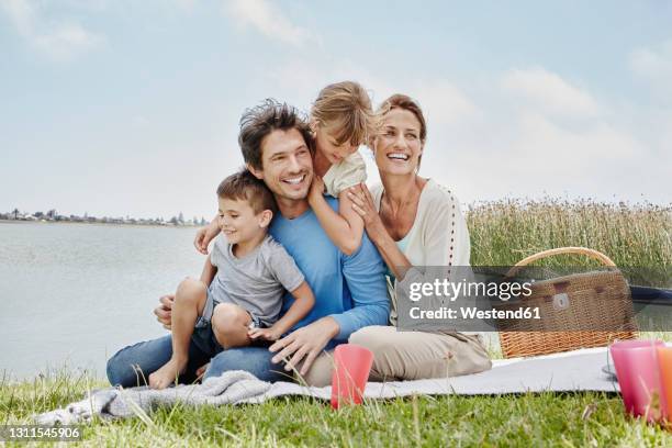 happy family sitting in a line on blanket by lake - 5 loch stock pictures, royalty-free photos & images