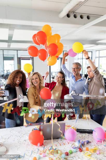 female entrepreneur taking selfie while celebrating birthday at desk in office - office party stock pictures, royalty-free photos & images