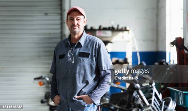 reifer mann arbeitet als automechaniker in der werkstatt - auto mechaniker stock-fotos und bilder