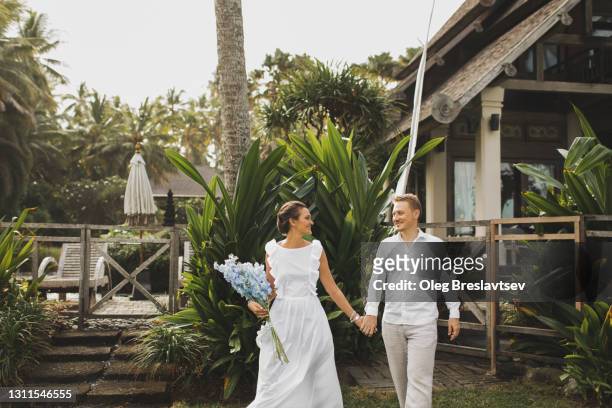 young and happy couple enjoying summer wedding day in tropical country house garden - destination wedding imagens e fotografias de stock