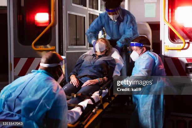 paramédicos cargan a paciente en ambulancia, con ebp - emergency services fotografías e imágenes de stock
