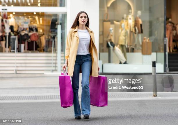 young woman walking with magenta colored shopping bags in front of store - madrid shopping stock pictures, royalty-free photos & images