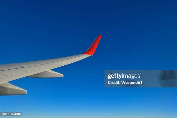wing of commercial airplane flying against clear blue sky - airplane clear sky stock pictures, royalty-free photos & images