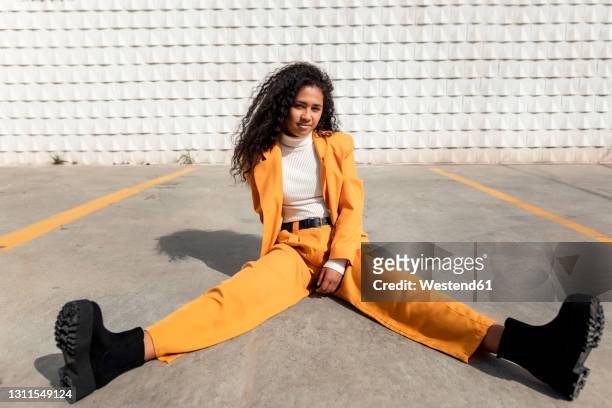 beautiful woman sitting with legs apart on footpath - breitbeinig stock-fotos und bilder