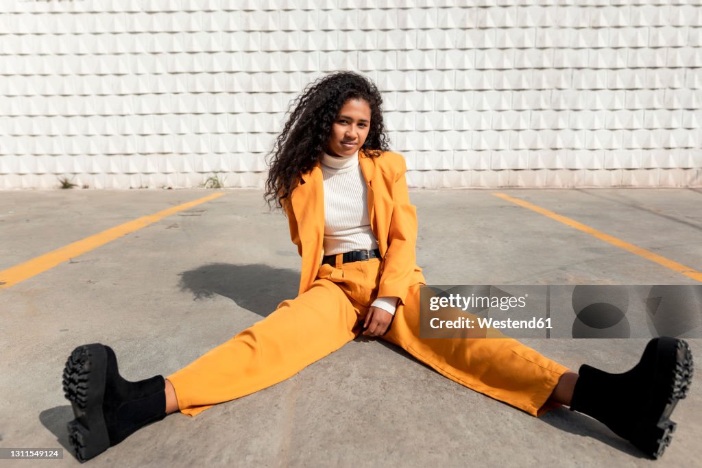 Beautiful woman sitting with legs apart on footpath