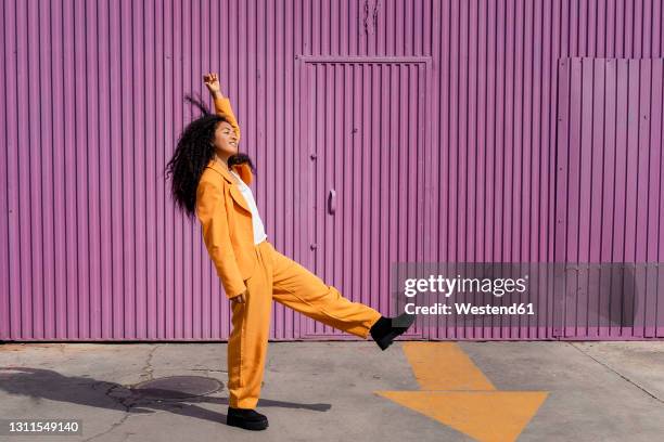 happy young woman dancing on footpath by cabin - pant suit stock pictures, royalty-free photos & images