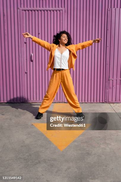 carefree woman with arms outstretched standing on footpath - legs spread fotografías e imágenes de stock