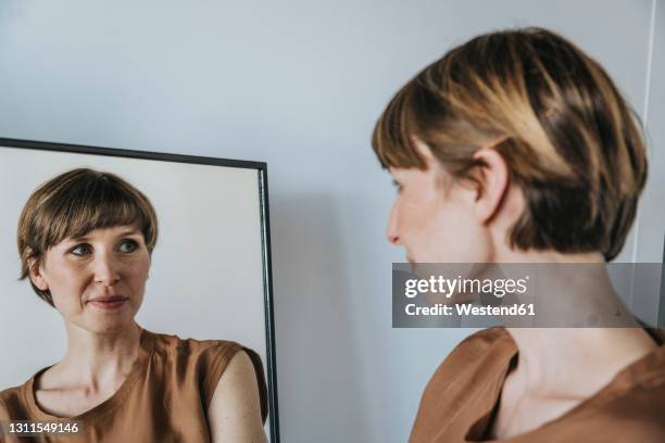 thoughtful woman looking at reflection in mirror - mirror reflection stock pictures, royalty-free photos & images