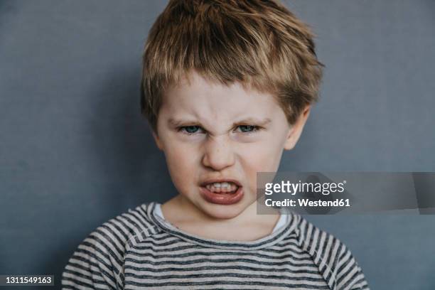 angry boy grimacing over gray background - anger stock pictures, royalty-free photos & images