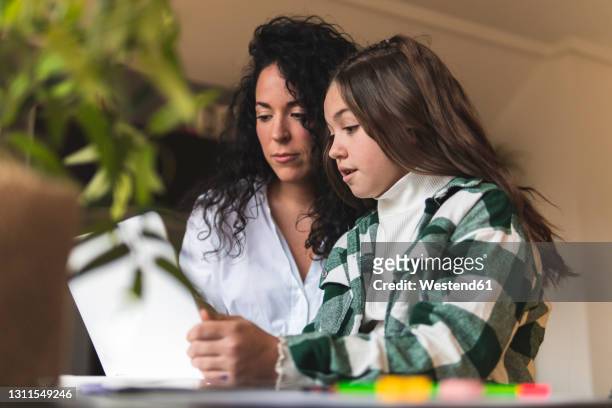 girl discussing with mother while e-learning through laptop at home - e girls stock pictures, royalty-free photos & images