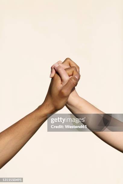 holding hands in front of white wall - incrociare foto e immagini stock