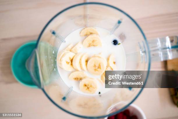 fresh bananas and milk in blender on table - blended drink ストックフォトと画像