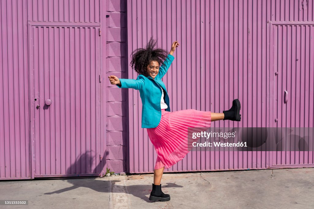 Carefree young woman dancing in front of purple cabin