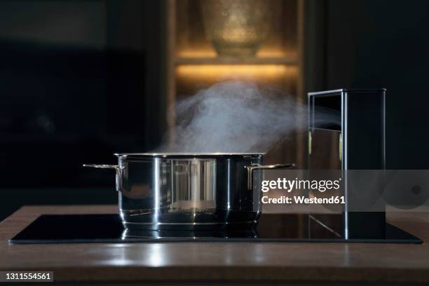 steam over saucepan on stove in kitchen - kochgeschirr stock-fotos und bilder