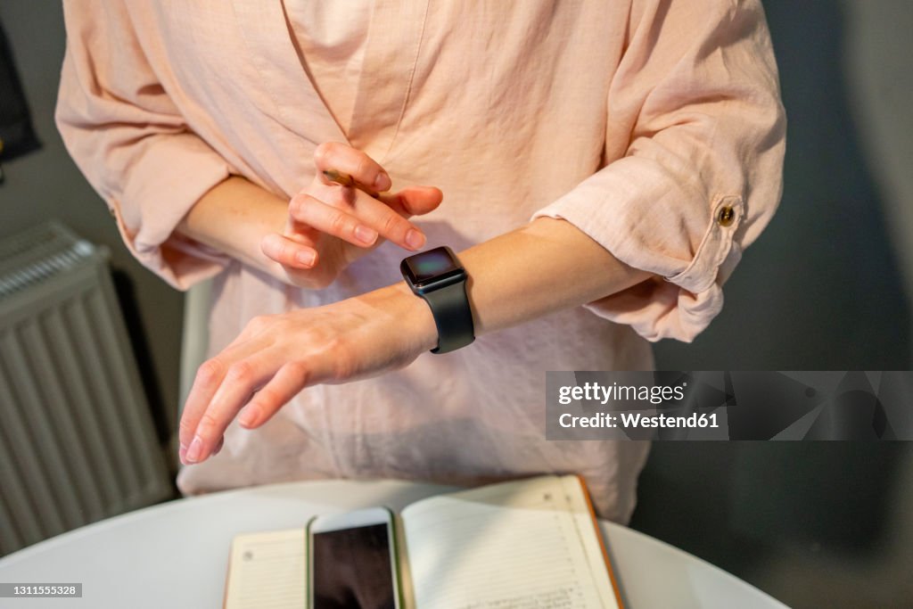 Young woman using smart watch at home