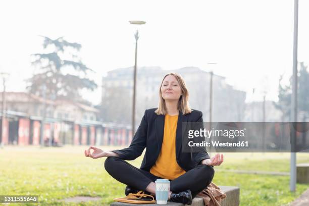 entrepreneur meditating while sitting at park - lotuspositie stockfoto's en -beelden