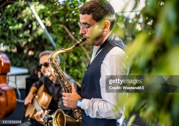 man playing saxophone while performing at event - jazz stock-fotos und bilder