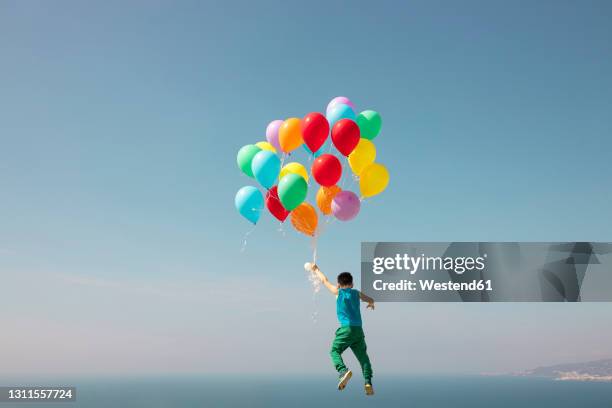 boy flying with bunch of balloons in sky - boy flying stock pictures, royalty-free photos & images