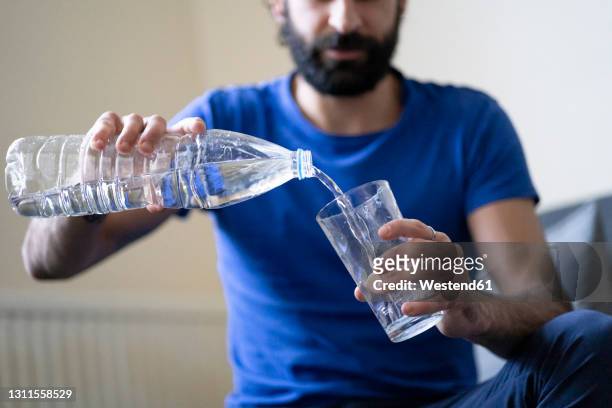 thirsty young man pouring water in drinking glass at home - törstig bildbanksfoton och bilder