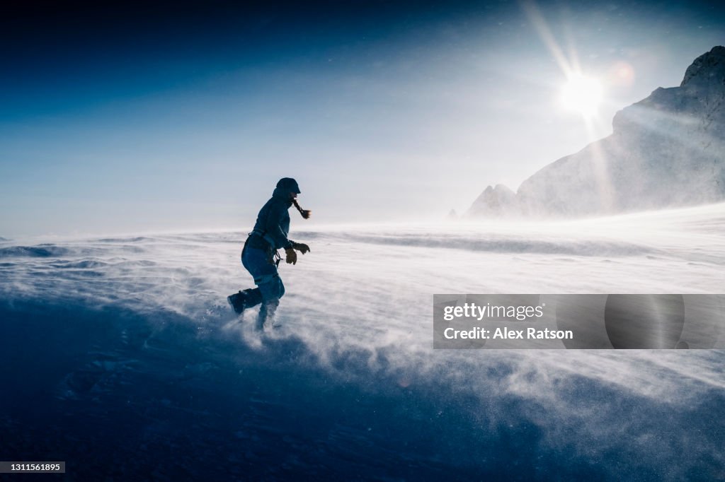 Women runs across glacier in strong winds