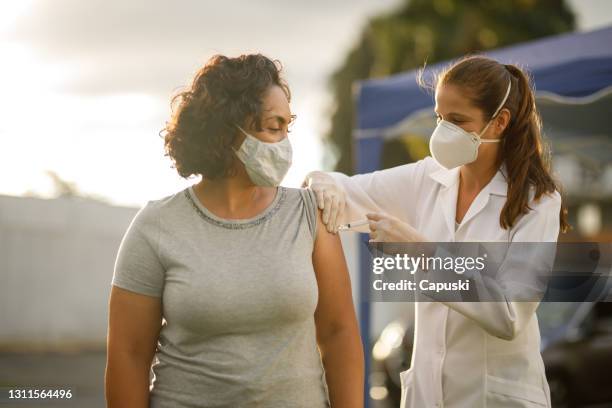 woman taking covid 19 vaccine - safe injecting stock pictures, royalty-free photos & images