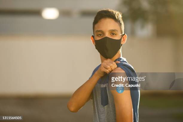 boy showing his covid 19 vaccine badge - latin america covid stock pictures, royalty-free photos & images