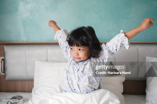 asian little child girl wakeup in the morning. stretching herself and exercise for relaxation - daily sport girls stock-fotos und bilder