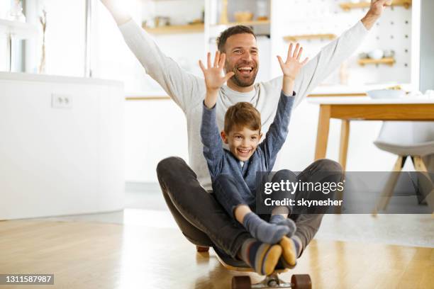 cheerful single father and son having fun on skateboard at home. - father longboard stock pictures, royalty-free photos & images