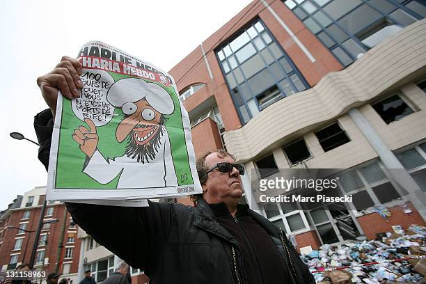 Man shows the French satirical magazine 'Charlie Hebdo', featuring a caricature of the Prophet Muhammad on its cover, following a petrol bomb attack...