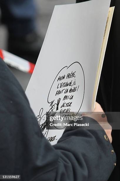 Journalist Mouloud Achour holds a cartoon in front of the offices of French satirical magazine 'Charlie Hebdo' following a petrol bomb attack on...