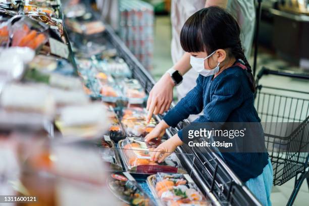 young asian mother and lovely little daughter with protective face mask choosing freshly packaged japanese sushi sets in supermarket. asian cuisine and food culture. convenience food to take away - スーパーマーケット　日本 ストックフォトと画像