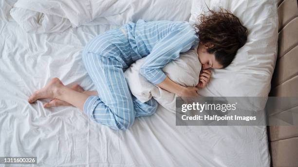 top view of depressed woman in pajamas lying in bed in bedroom. - sleeping woman stock-fotos und bilder