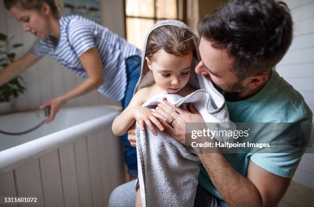 family with small daughter in bathroom at home, drying after evening bath. - bath towels stock-fotos und bilder