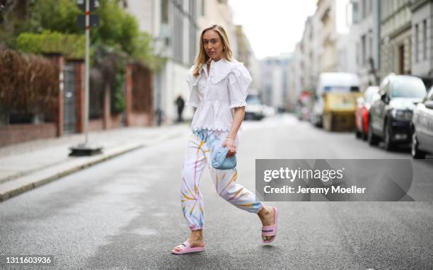 Sonia Lyson wearing baby blue Bottega Veneta mini pouch, pink Balenciaga sandals, Sprwmn Los Angeles tie dye sweatpants and white horror vacui blouse...